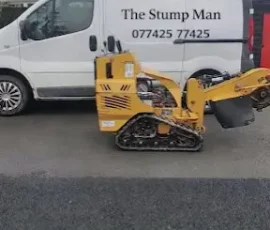 Yellow stump grinder in front of white van
